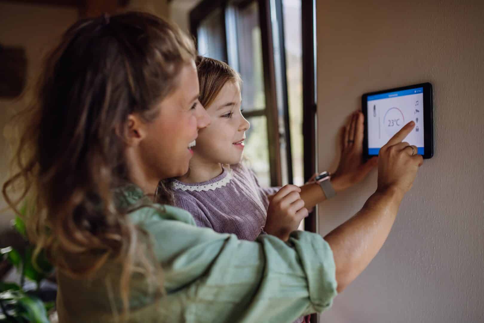 A young family adjusting their home’s smart thremostat